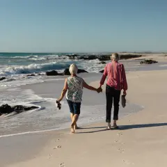 Para świętuje 70 rocznicę ślubu, spacerując boso po plaży, trzymając się za ręce.