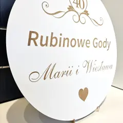 Okrągła tablica z napisem "Rubinowe Gody" i imionami Marii i Wiesława. Rubinowe gody to 40 lat wspólnego życia.