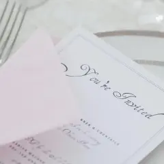 Eleganckie zaproszenie z napisem "You're Invited" i różową kopertą. Wskazówka, jak pisać na zaproszeniu z osobą towarzyszącą.