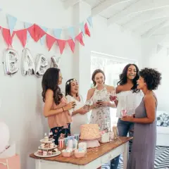 Radosne kobiety świętują baby shower. Balony z napisem "BABY", girlandy i tort tworzą atmosferę. To idealne miejsce, by dowiedzieć się, baby shower co to jest!