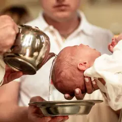 Kto trzyma dziecko do chrztu? Kapłan polewa głowę niemowlęcia wodą święconą.