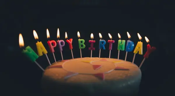Płonące świeczki w kształcie liter tworzą napis "Happy Birthday". Idealne na życzenia urodzinowe po angielsku.