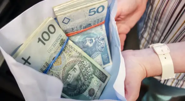Koperta z pieniędzmi, prezent od cioci i wujka na osiemnastkę. Stosy banknotów 100 i 50 zł.