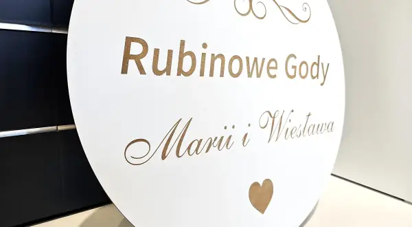 Okrągła tablica z napisem "Rubinowe Gody" i imionami Marii i Wiesława. Rubinowe gody to 40 lat wspólnego życia.