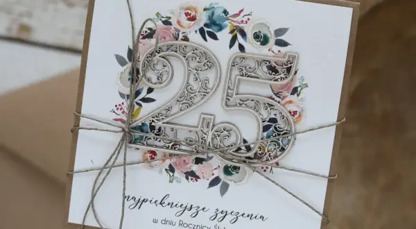 Elegancka kartka z napisem "najpiękniejsze życzenia w dniu Rocznicy Ślubu" i ozdobnym numerem 25, otoczonym kwiatami.