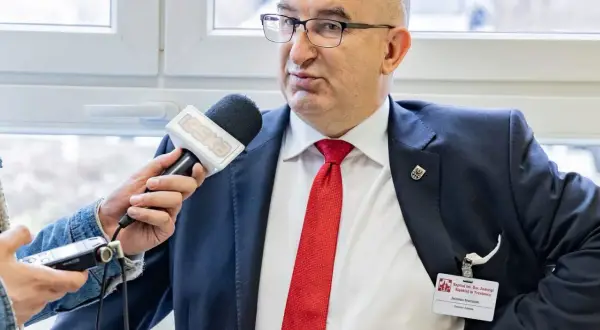 Mężczyzna w garniturze i czerwonym krawacie udziela wywiadu z mikrofonem Radia Eska.