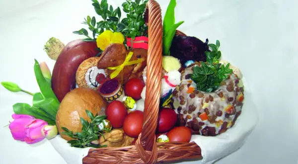 Koszyk wielkanocny z tradycyjnym święceniem pokarmów: chleb, kiełbasa, jajka, babka, zieleń i ozdoby.
