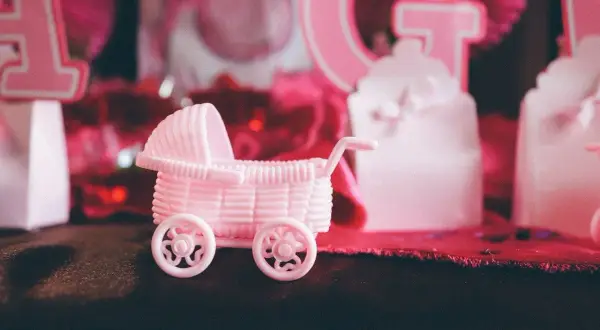 Różowy wózek dla lalek na przyjęciu gender reveal. Czy to będzie dziewczynka?