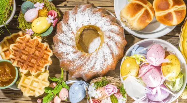Kiedy jest śniadanie wielkanocne: babka, gofry, jajka w koszyczkach i bułeczki na drewnianym stole.