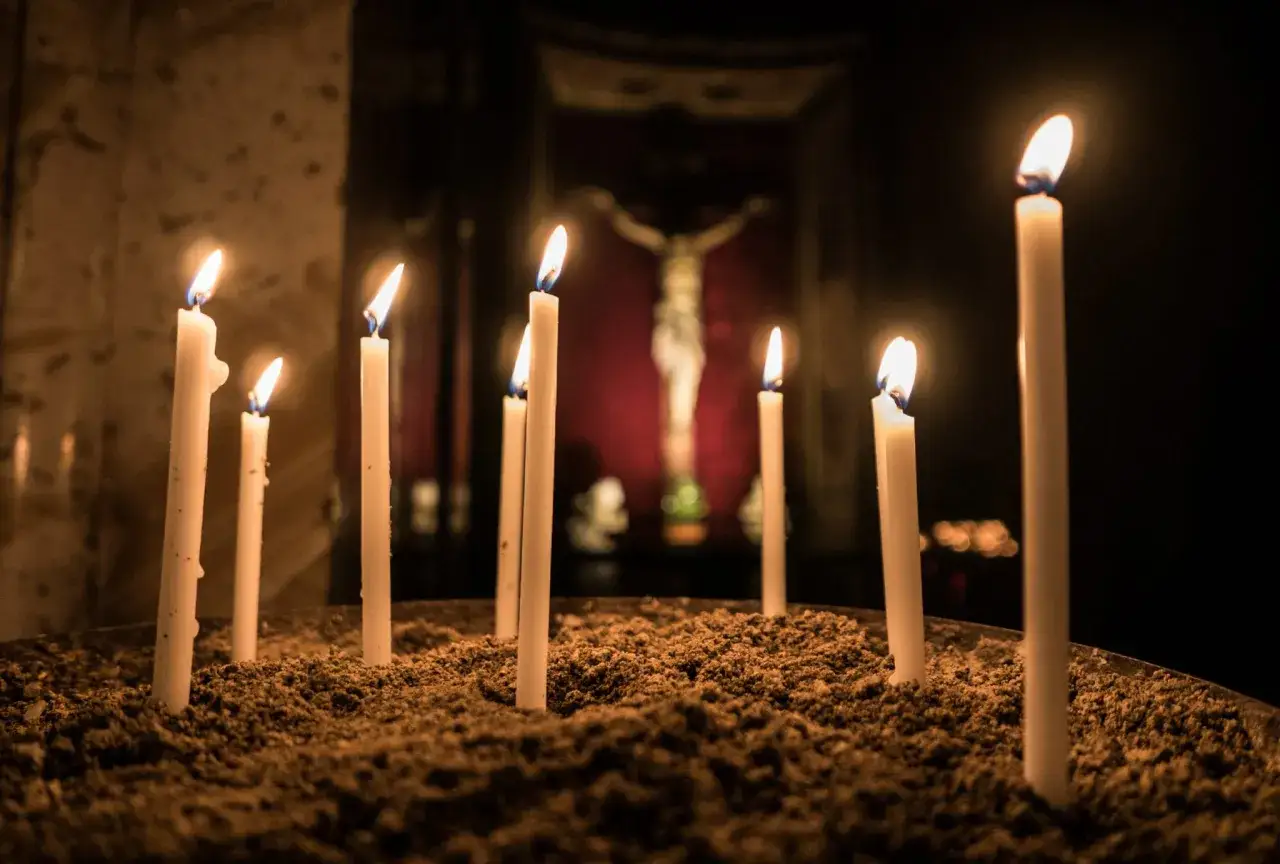 Płonące świece w kościele, symbolizujące codzienna modlitwa do ducha świętego. W tle widać krzyż.