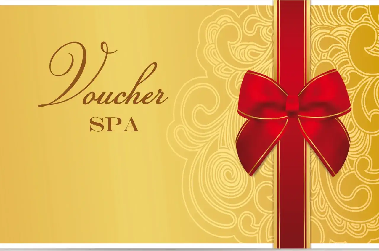 Elegancki złoty voucher do SPA z czerwoną wstążką i kokardą. Idealny prezent dla bliskiej osoby.