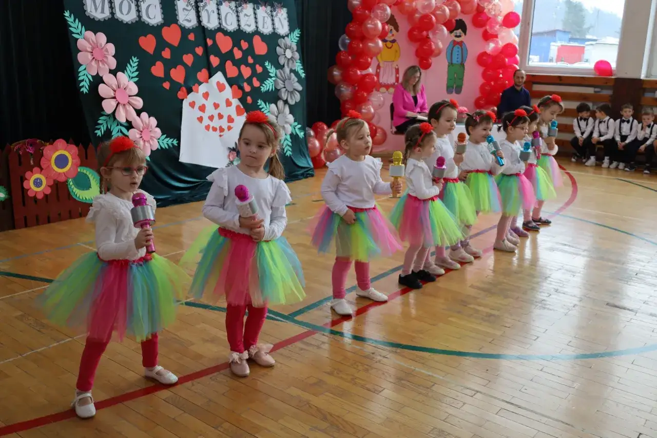 Dzieci w kolorowych spódniczkach śpiewają piosenkę na Dzień Dziecka.